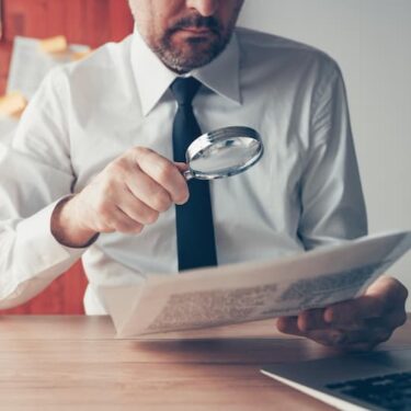 Un homme en chemise étudie un document avec une loupe