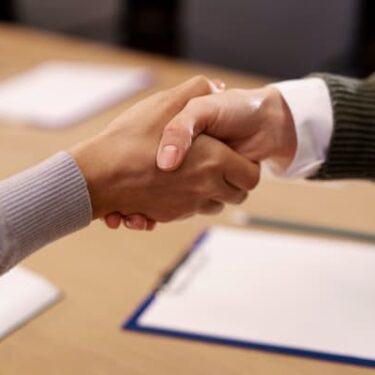 Deux personnes se serrant la main au-dessus d'un bureau avec des documents