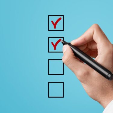 Main tenant un stylo noir cochant des cases de validation sur fond bleu