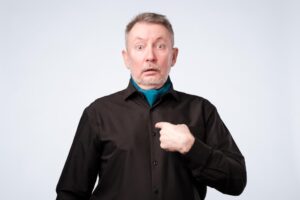 Homme d'âge mûr se désignant du doigt avec un air surpris, illustrant la notion d'intuitu personae